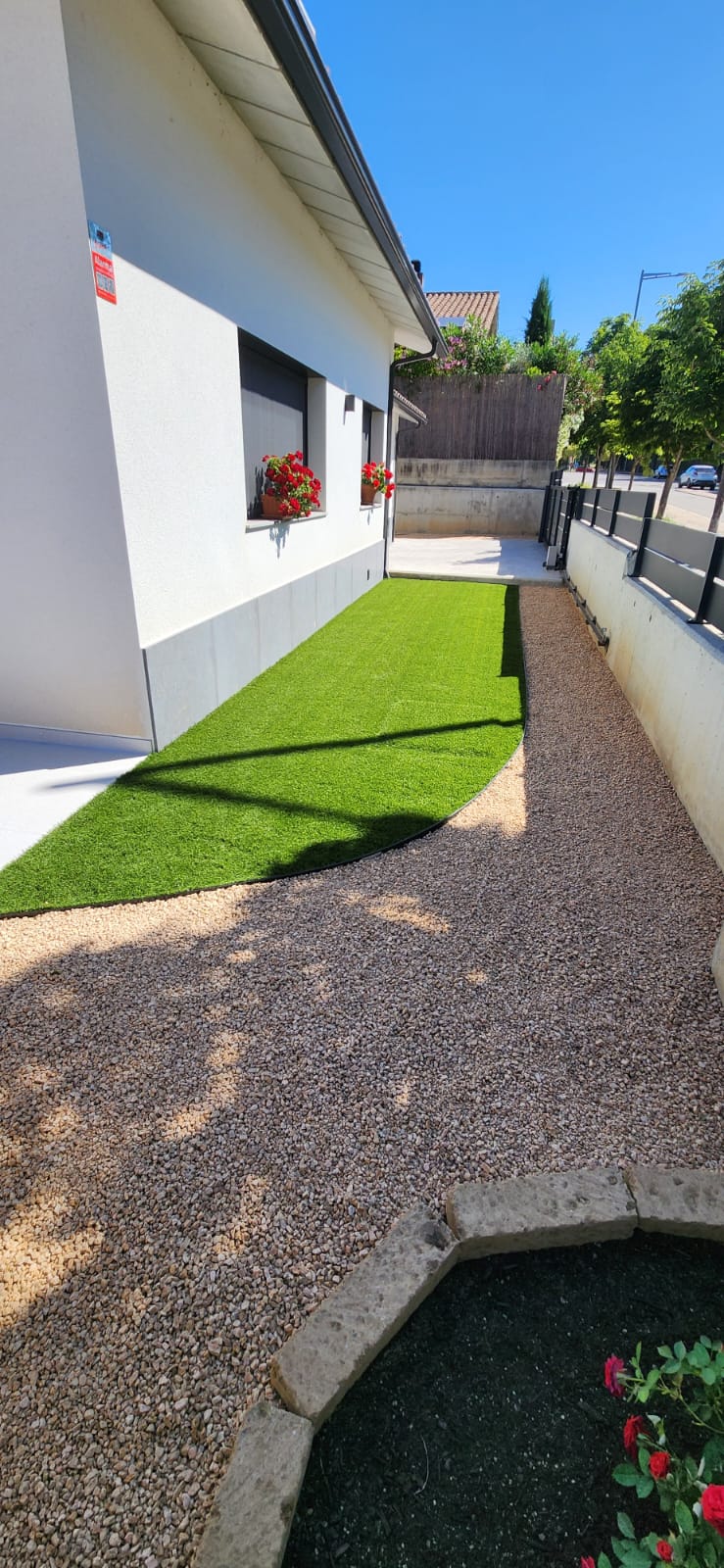 Pas lateral amb gespa artificial i grava decorativa a Osona