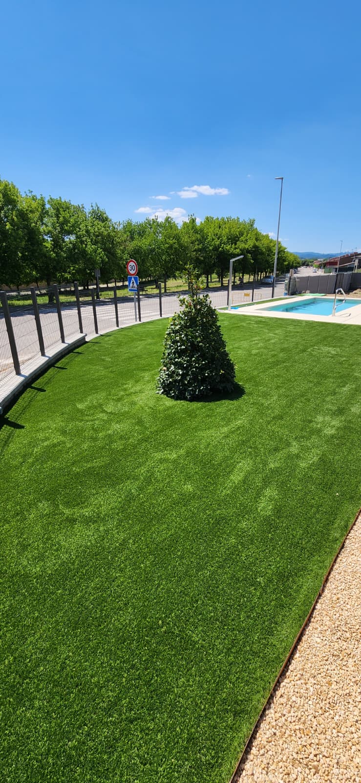 Gespa artificial instal·lada al costat de tanca i piscina a Osona